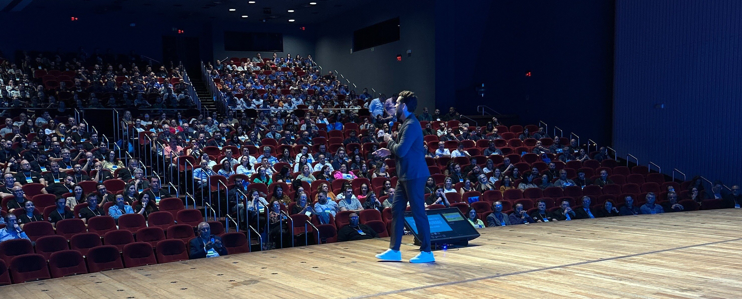 Gustavo Malavota palestrando no palco com público